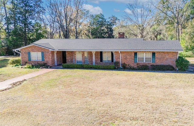 ranch-style home featuring a chimney, brick siding, and a front yard