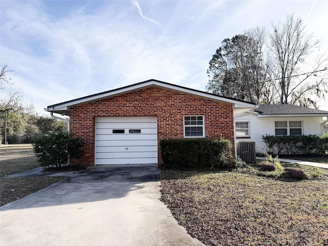 view of property exterior featuring a garage, brick siding, central air condition unit, and concrete driveway