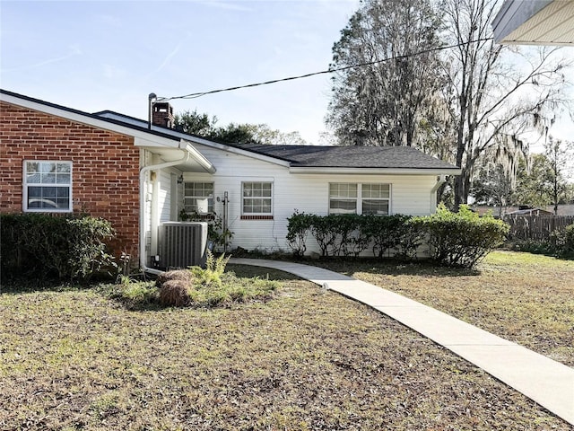 view of front of house featuring cooling unit, brick siding, and a chimney