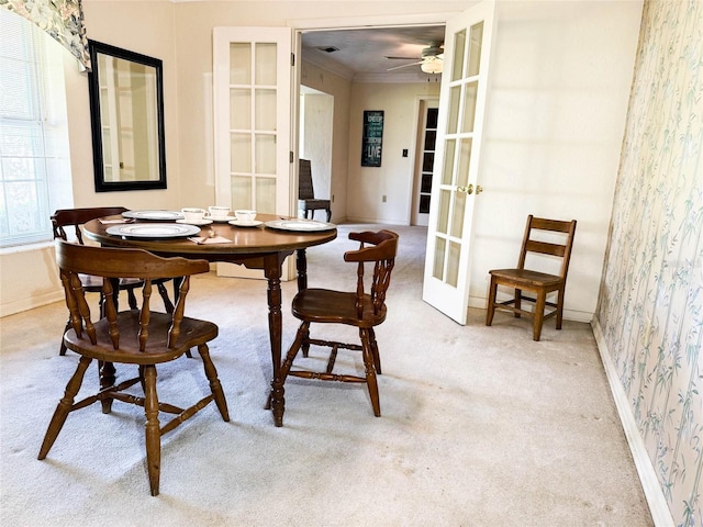 dining area featuring french doors, carpet flooring, wallpapered walls, ceiling fan, and crown molding