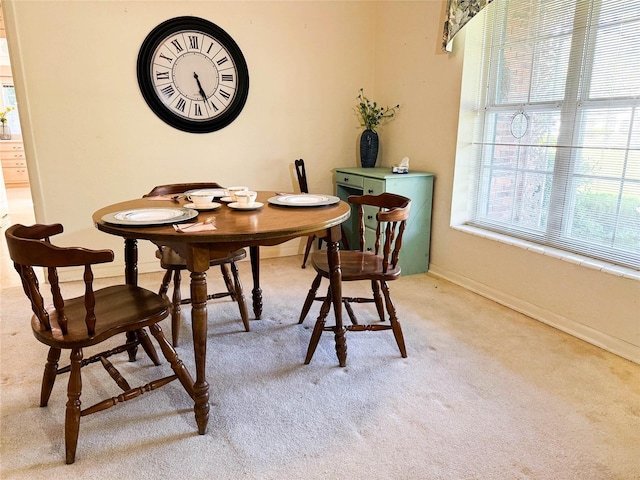 dining room featuring baseboards and light colored carpet