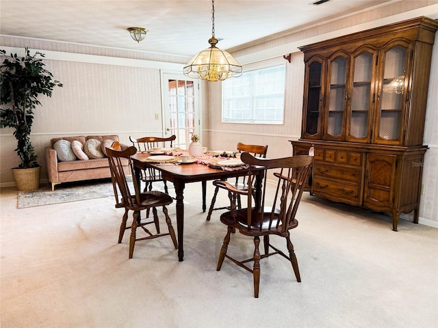 dining room featuring a chandelier, crown molding, and light colored carpet