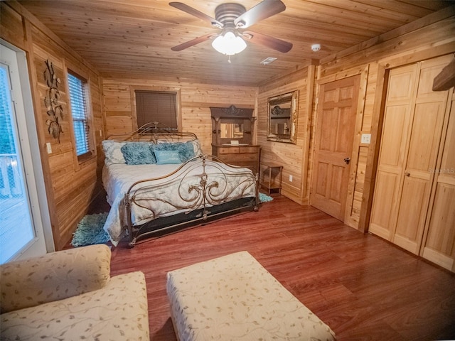 bedroom with ceiling fan, wood walls, and wooden ceiling