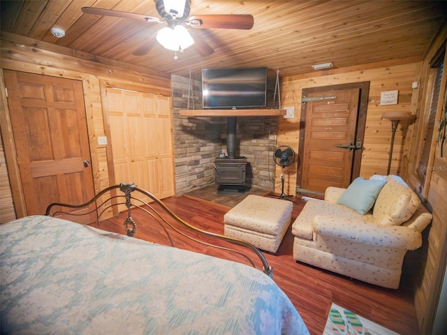 bedroom featuring ceiling fan, a wood stove, hardwood / wood-style flooring, and wooden ceiling