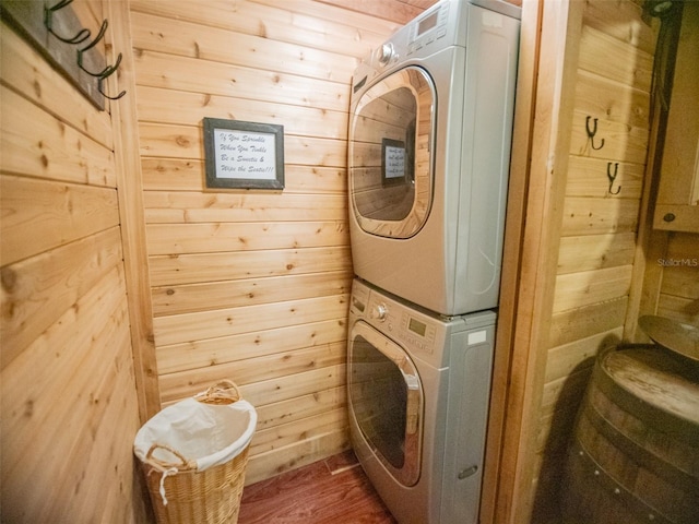 washroom featuring stacked washer / dryer and wooden walls