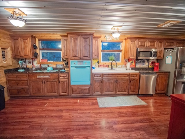 kitchen with sink, dark hardwood / wood-style floors, dark stone counters, and stainless steel appliances