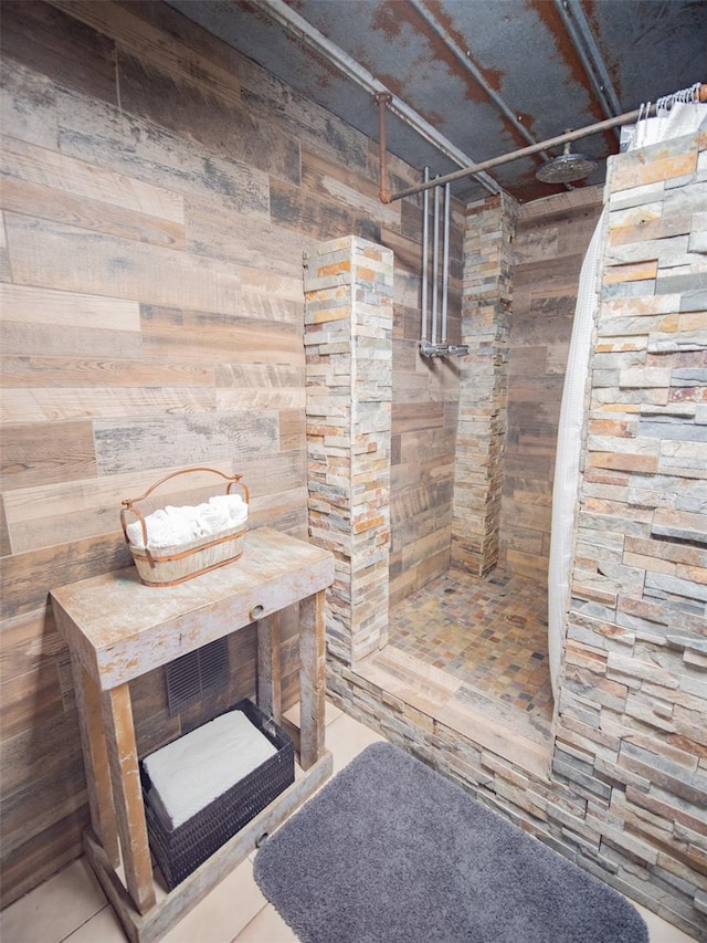 bathroom with tile patterned floors, wood walls, and walk in shower