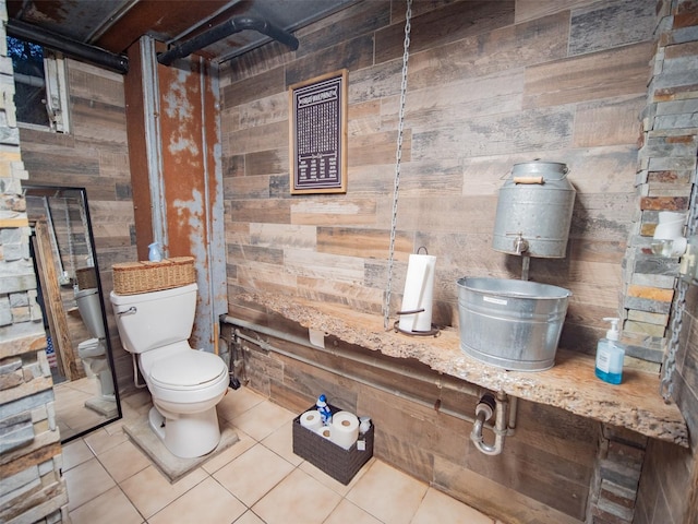 bathroom with wood walls, toilet, and tile patterned floors