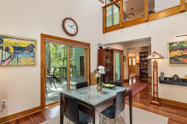 dining space featuring a towering ceiling and dark hardwood / wood-style flooring