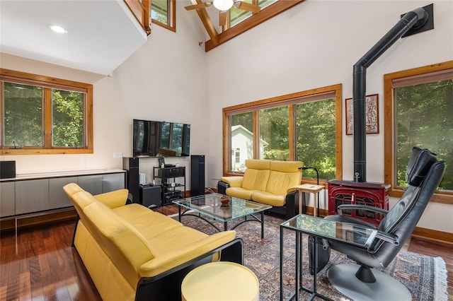 living room with ceiling fan, dark hardwood / wood-style floors, a towering ceiling, and a wood stove