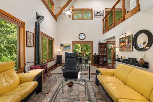 living room featuring a wood stove, high vaulted ceiling, ceiling fan, and beam ceiling