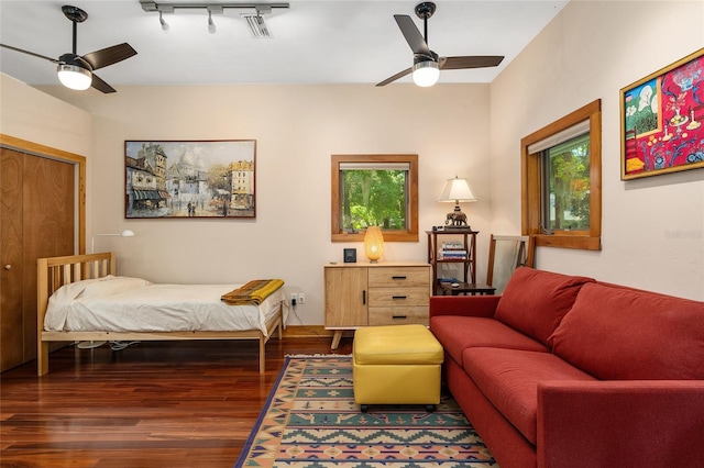 bedroom with ceiling fan, multiple windows, dark hardwood / wood-style flooring, and track lighting