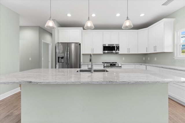 kitchen featuring stainless steel appliances, pendant lighting, a kitchen island with sink, and sink