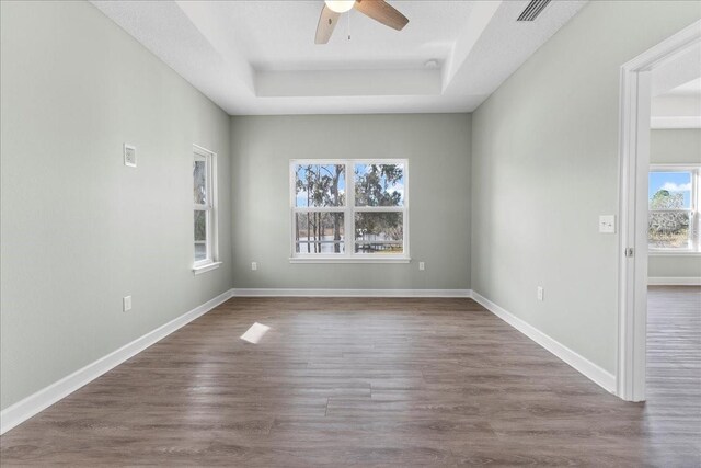 spare room with ceiling fan, dark hardwood / wood-style flooring, and a tray ceiling