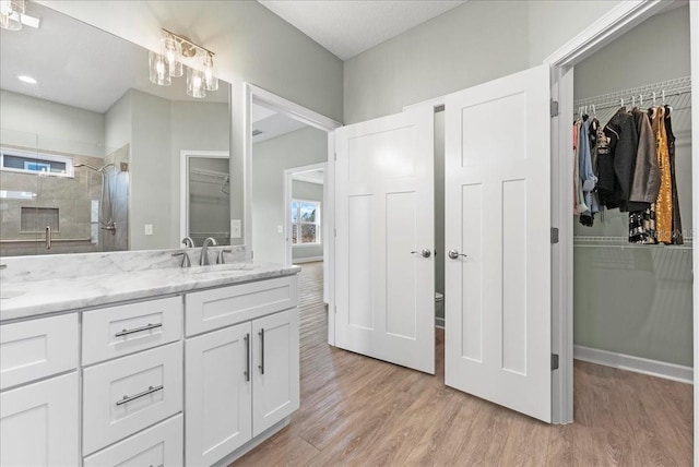 bathroom featuring hardwood / wood-style flooring, vanity, and tiled shower