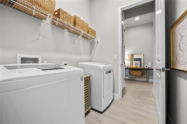 clothes washing area featuring light wood-type flooring, washer and dryer, recessed lighting, baseboards, and laundry area