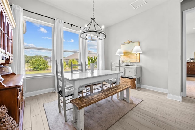 dining space featuring light wood-type flooring and a notable chandelier