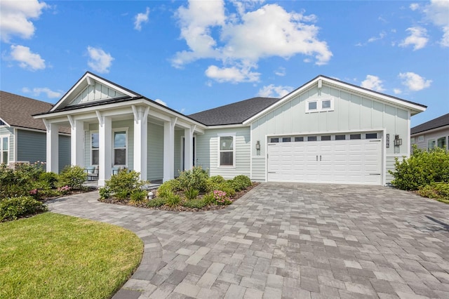 view of front of house with board and batten siding, an attached garage, decorative driveway, and roof with shingles