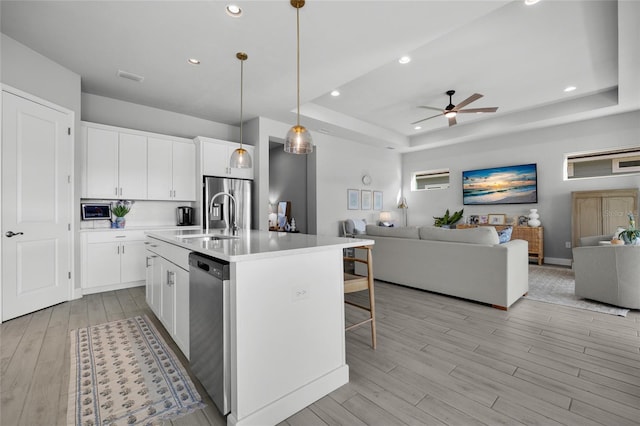 kitchen featuring open floor plan, stainless steel appliances, a tray ceiling, and a sink