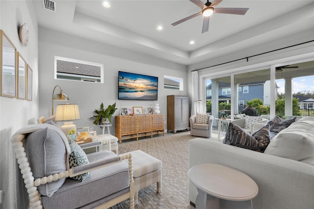 carpeted living area with a tray ceiling, recessed lighting, a ceiling fan, and visible vents