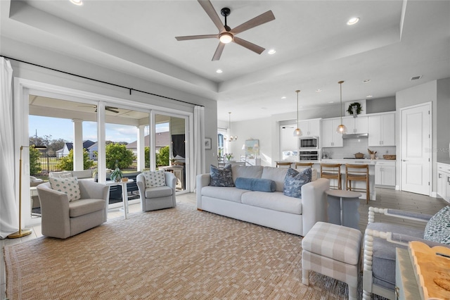 living area featuring recessed lighting, a tray ceiling, visible vents, and ceiling fan