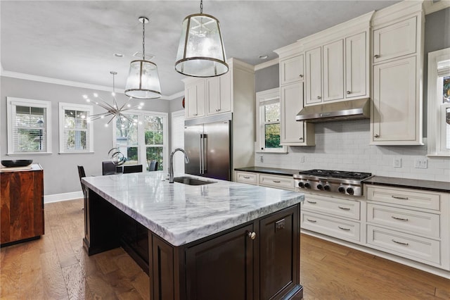 kitchen featuring dark wood-type flooring, stainless steel appliances, hanging light fixtures, and a center island with sink