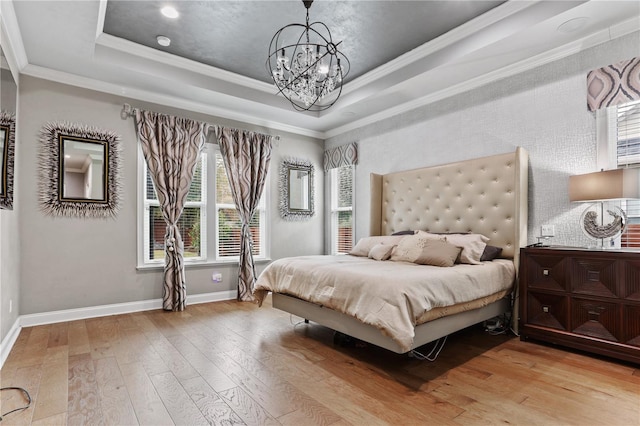 bedroom with crown molding, a notable chandelier, a tray ceiling, and light hardwood / wood-style flooring