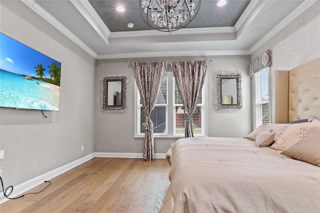 bedroom with an inviting chandelier, hardwood / wood-style floors, a tray ceiling, and ornamental molding