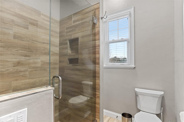 bathroom with a shower with door and toilet