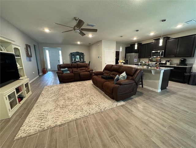 living room featuring ceiling fan and a textured ceiling