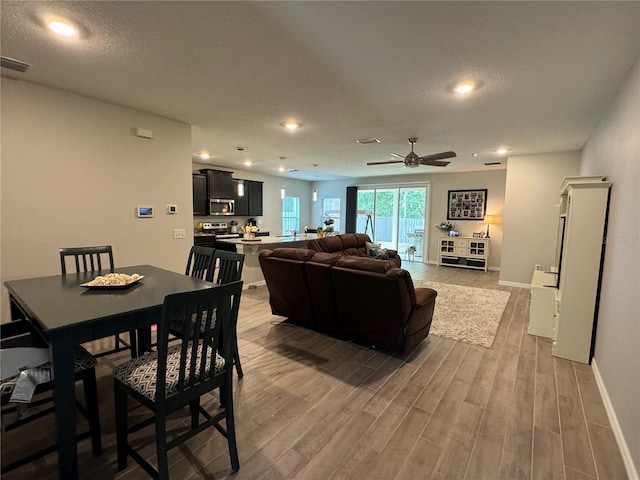 dining room featuring ceiling fan, light hardwood / wood-style flooring, and a textured ceiling