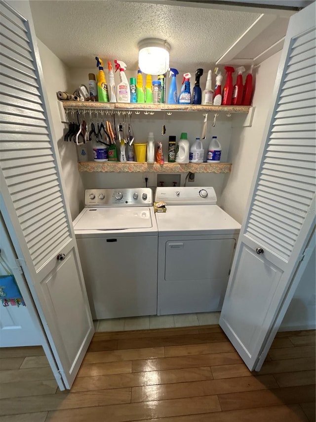 laundry room with dark wood-type flooring, a textured ceiling, and washer and clothes dryer