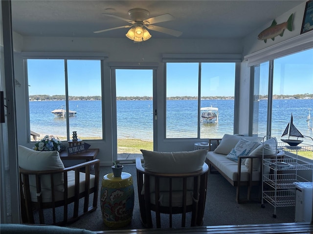 sunroom / solarium featuring plenty of natural light, ceiling fan, and a water view