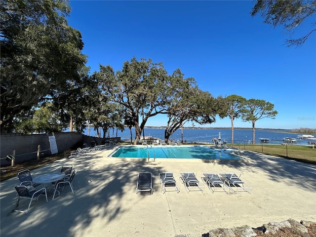 view of swimming pool featuring a patio and a water view