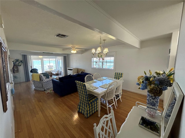 dining room with hardwood / wood-style flooring, ceiling fan with notable chandelier, and a textured ceiling