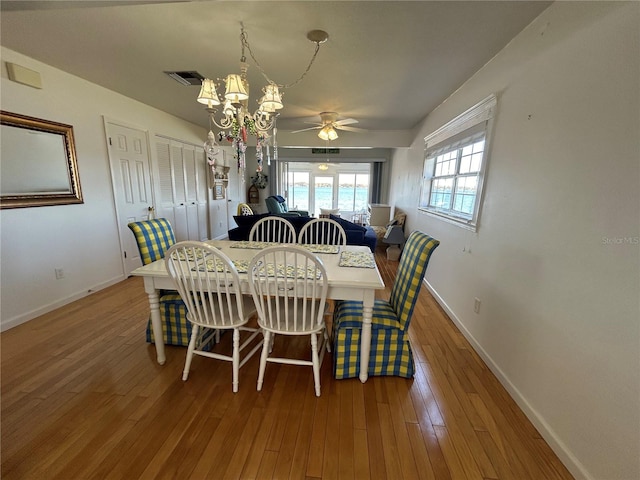 dining area with ceiling fan with notable chandelier and hardwood / wood-style floors