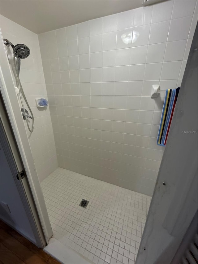 bathroom with wood-type flooring and a tile shower