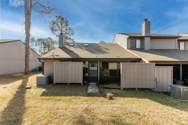 rear view of property featuring central AC unit and a lawn