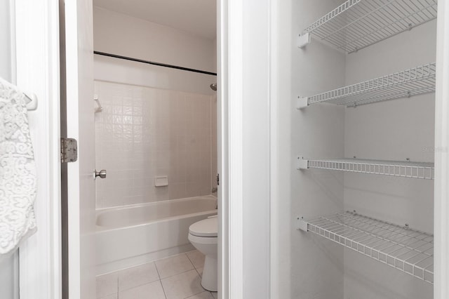 bathroom featuring tiled shower / bath, tile patterned floors, and toilet