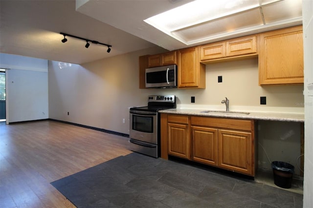 kitchen featuring sink, dark wood-type flooring, stainless steel appliances, and rail lighting