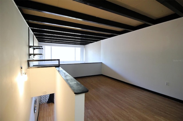 empty room featuring beamed ceiling and dark hardwood / wood-style floors