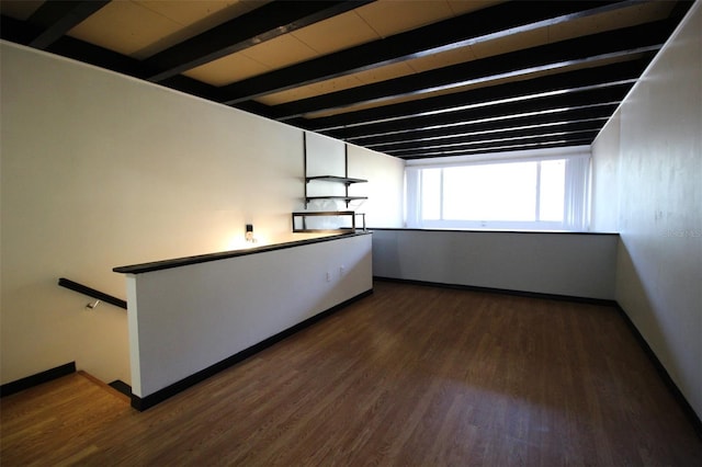 empty room with beamed ceiling and dark hardwood / wood-style flooring