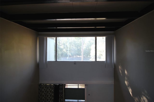 spare room with beamed ceiling and a healthy amount of sunlight