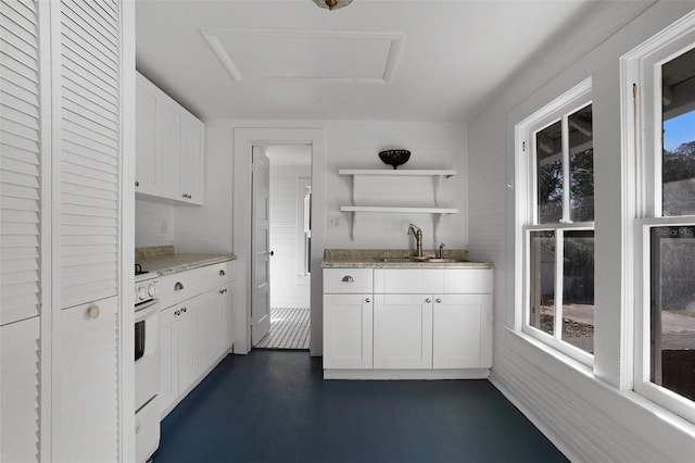 kitchen with dark wood-type flooring, sink, light stone counters, white gas range, and white cabinets