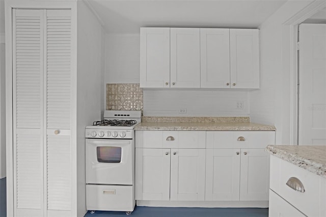 kitchen with tasteful backsplash, white cabinets, and gas range gas stove