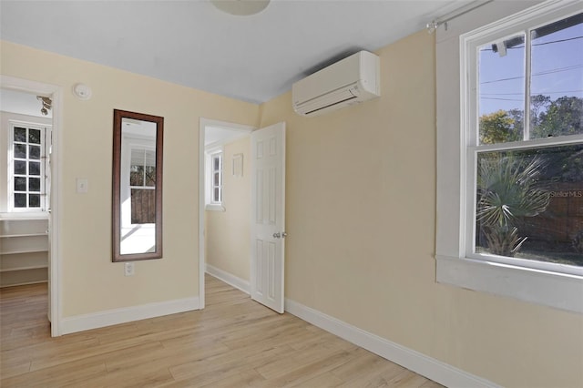 unfurnished room featuring light hardwood / wood-style floors and a wall unit AC