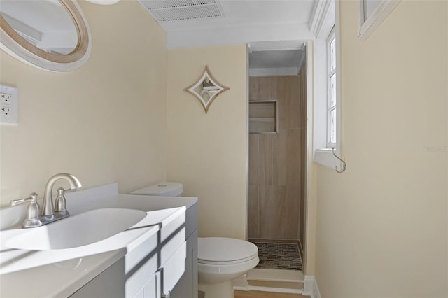 bathroom featuring tiled shower, vanity, and toilet