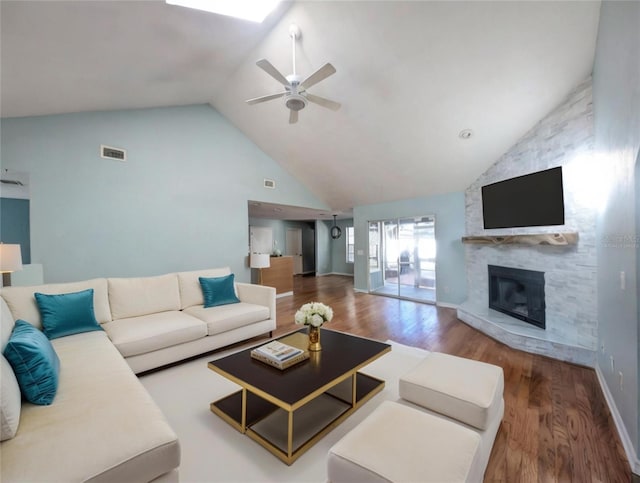 living room featuring hardwood / wood-style flooring, ceiling fan, vaulted ceiling, and a fireplace