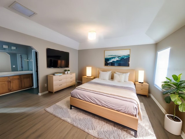 bedroom with dark wood-type flooring and ensuite bath