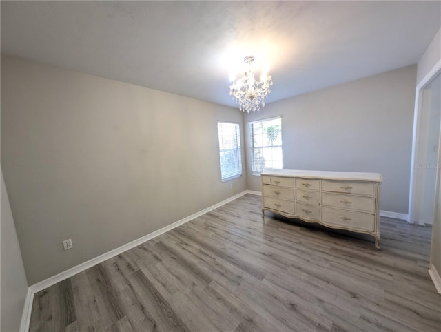 unfurnished bedroom featuring a notable chandelier and light wood-type flooring